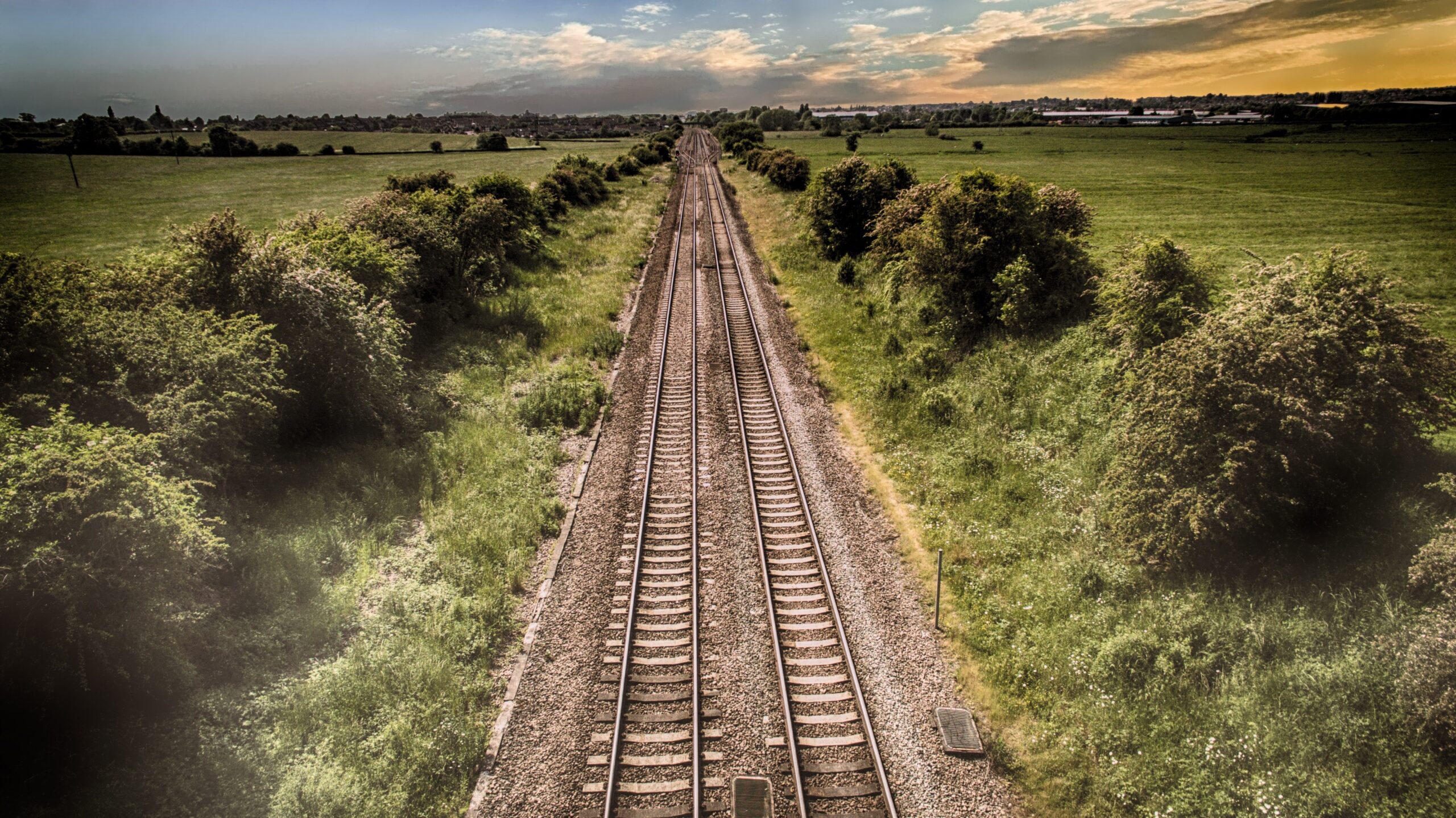 train tracks thinning to vanishing point through landscape with